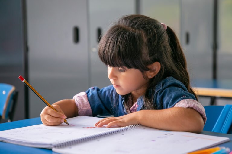 Pensive black haired Latin girl sitting at school desk